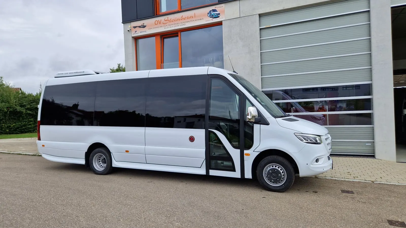 Minibus Mercedes Sprinter z przeszklonym dachem przed zakładem Midibusse